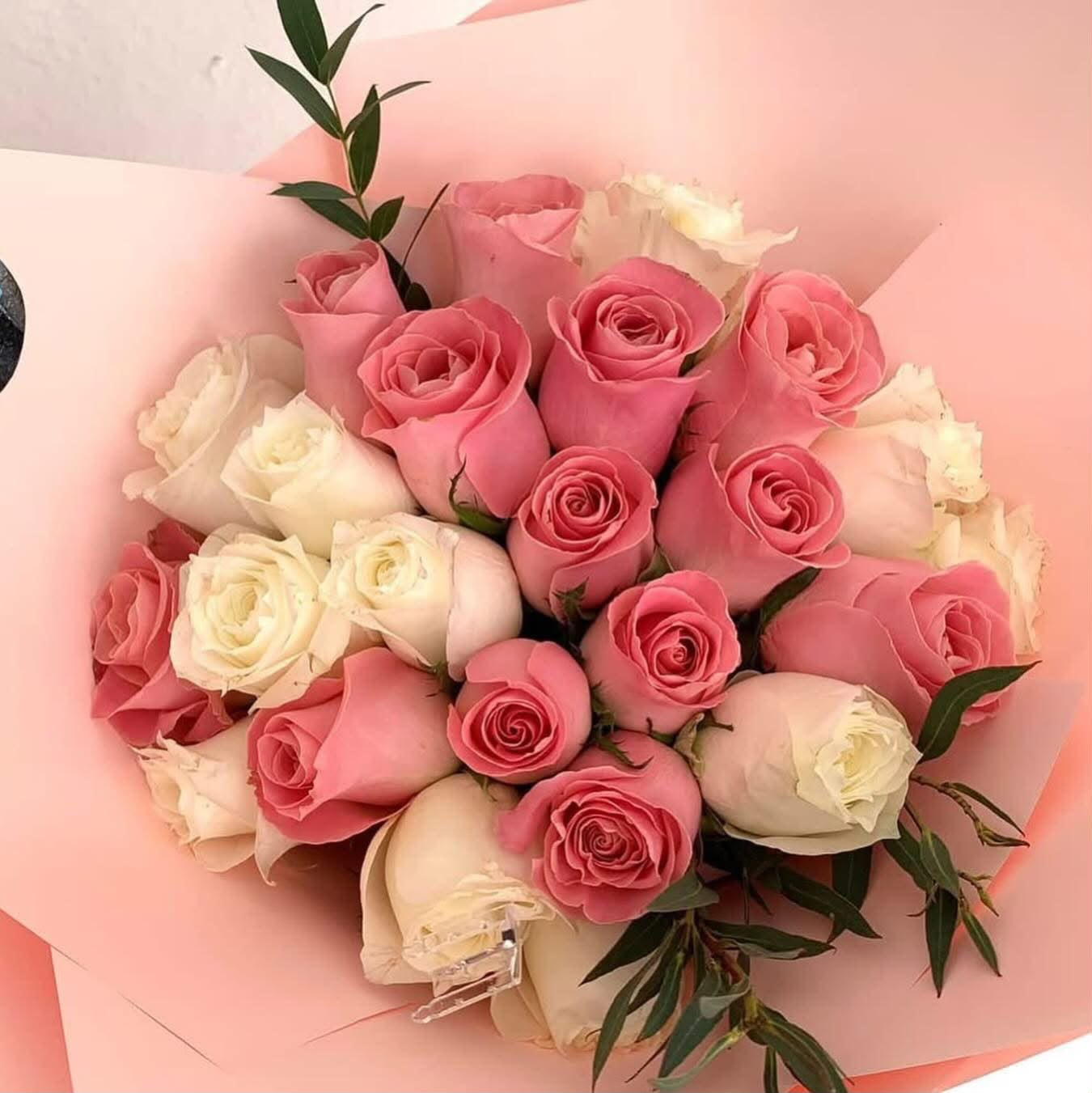 Ramo de rosas rosadas y blancas envuelto en papel rosa