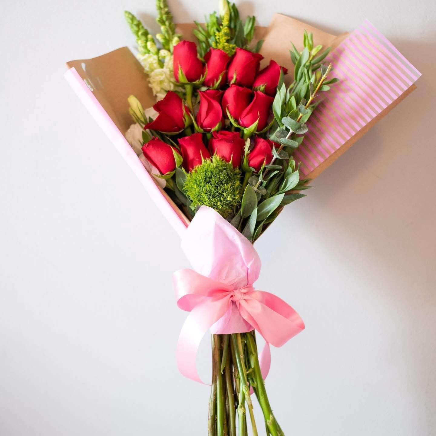 Ramo de rosas rojas con follaje y lazo rosa