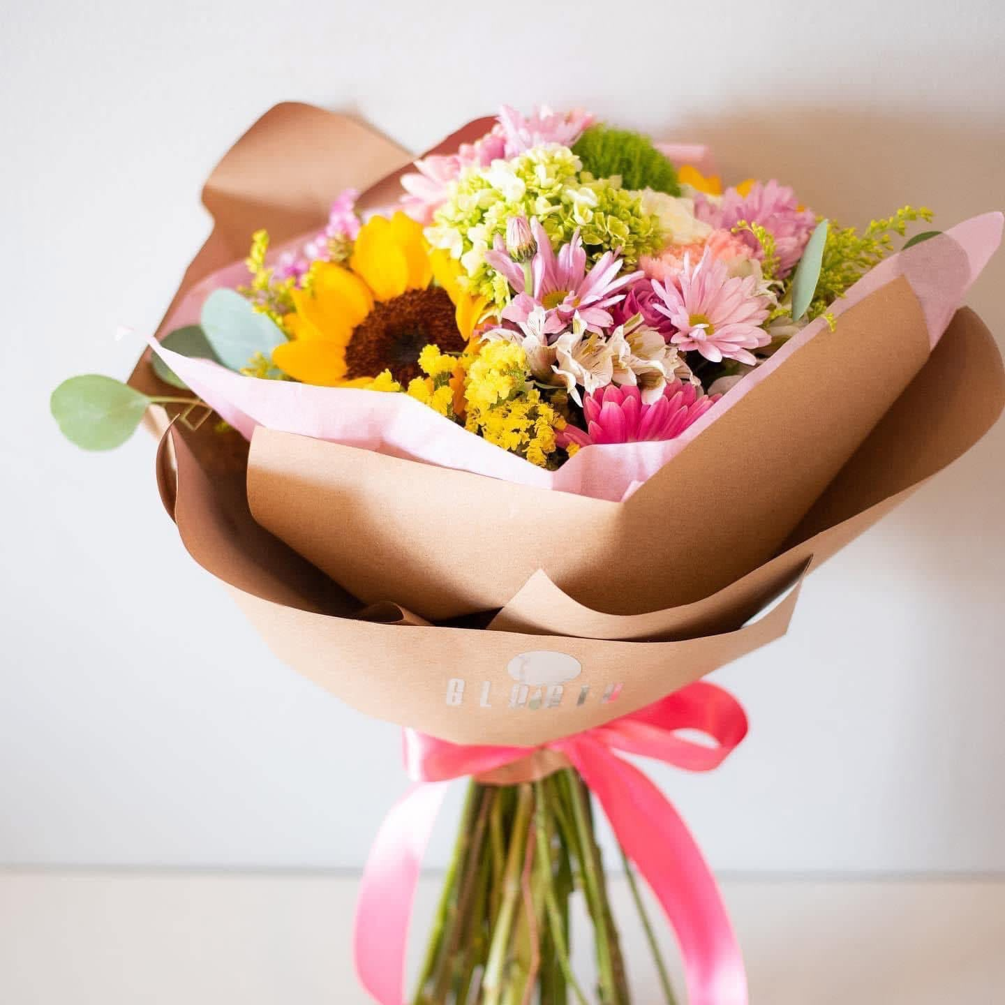 Ramo mixto con girasol y flores rosadas envuelto en papel kraft