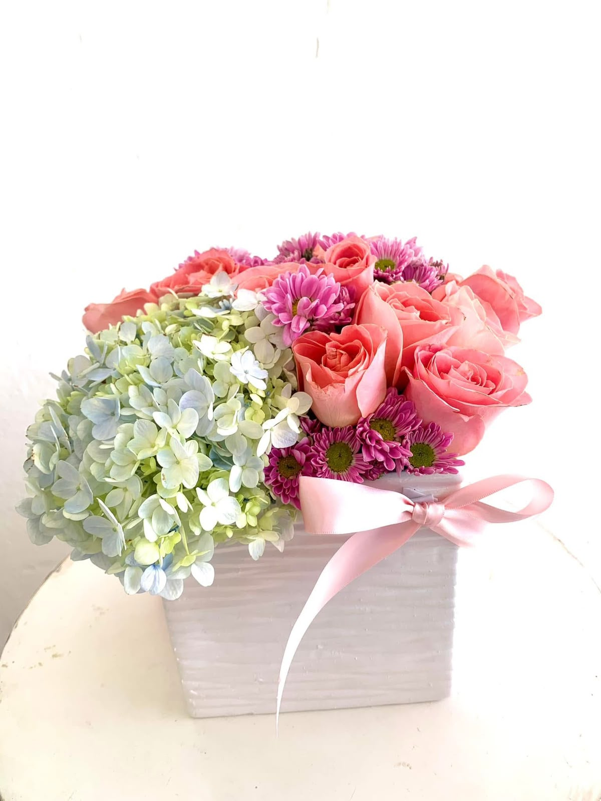 Arreglo floral en maceta blanca con hortensias, rosas y crisantemos