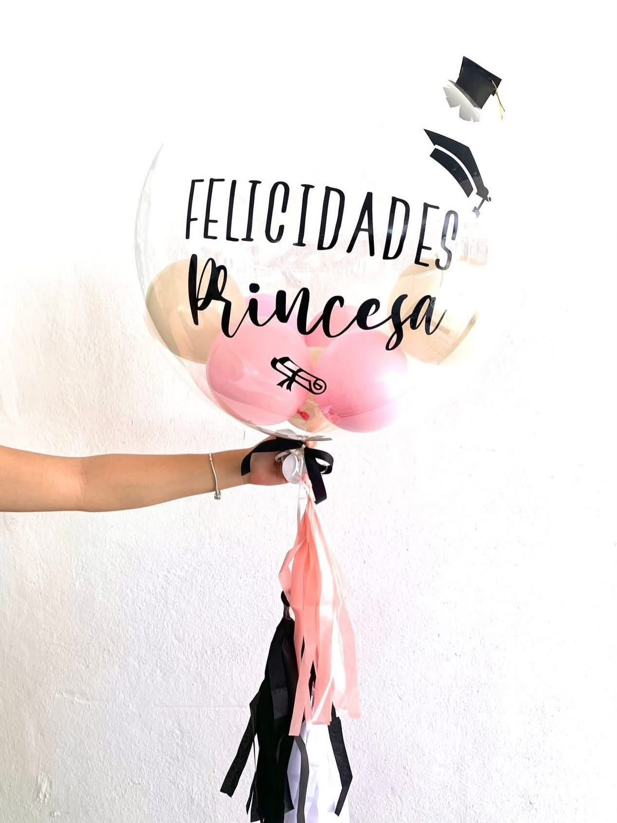 Globo transparente de graduación en tonos rosa y negro con el mensaje Felicidades Princesa